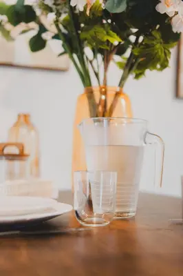 a glass of water next to a vase with flowers at T2 cosy tout équipé, parking et wifi gratuit, Castres in Castres