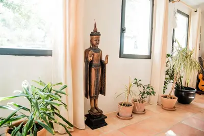 a statue of a god in a room with plants at La Colline aux Oiseaux - Quatre chambres in Fa