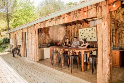 a group of people sitting at a table on a deck at La Colline aux Oiseaux - Quatre chambres in Fa