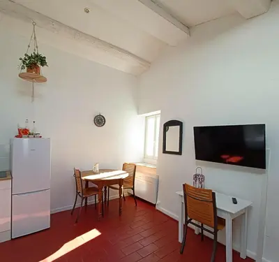 a kitchen and dining room with a table and a refrigerator at la guitoune du pélican halte à vélo in Puisserguier