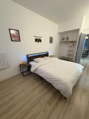 a large bed in a room with a wooden floor at Comme à la maison in Carcassonne