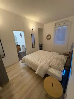 a bedroom with a large bed and a wooden table at Comme à la maison in Carcassonne