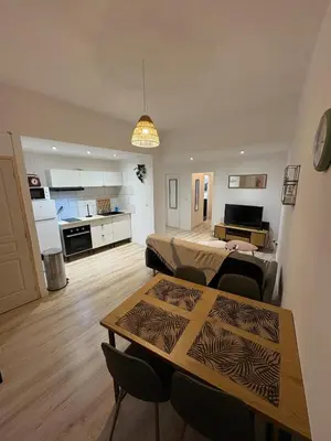 a living room with a table and a kitchen at Comme à la maison in Carcassonne
