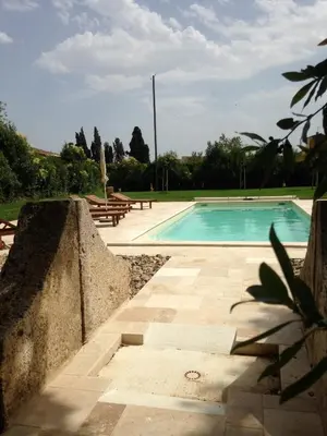 a swimming pool in a yard with benches around it at Domaine Paul Huc in Fabrezan