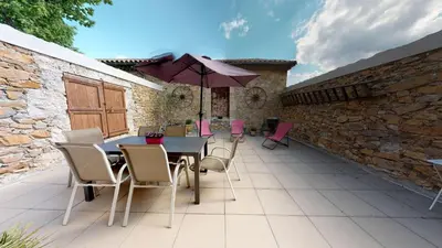 a patio with a table and chairs and an umbrella at Domaine Paul Huc in Fabrezan