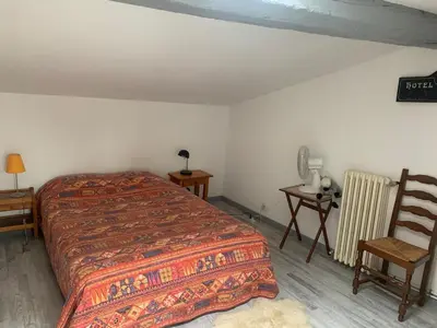 a bedroom with a bed and a chair and a table at appartement T3 duplex centre de Castelnaudary in Castelnaudary