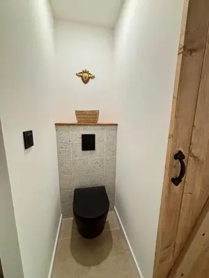 a bathroom with a toilet with a black seat at La Table du Chevalier - Cité in Carcassonne