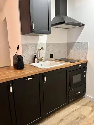 a kitchen with black cabinets and a white sink at La Table du Chevalier - Cité in Carcassonne