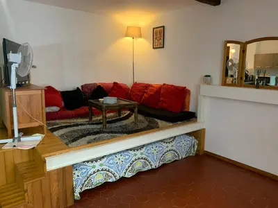 a living room with a red couch and a table at grand studio avec terrasse centre Castelnaudary in Castelnaudary