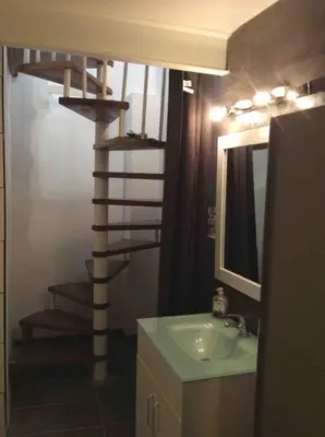 a bathroom with a sink and a spiral staircase at grand studio avec terrasse centre Castelnaudary in Castelnaudary