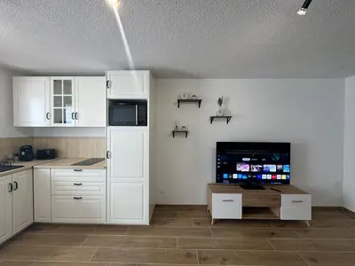 a kitchen with white cabinets and a flat screen tv at Vacances à Gruissan in Gruissan