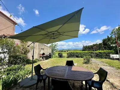 a table and chairs with a green umbrella at Maison tout confort proche centre avec jardin in Carcassonne