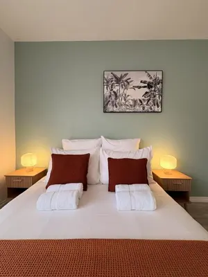 a bedroom with a large white bed with two lamps at L'appartement Rome Antique - Climatisation - Terrasse in Narbonne