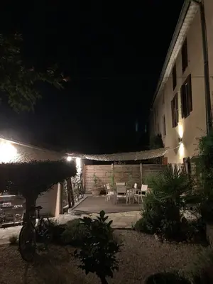 an outdoor patio at night with a table and chairs at Le jardin du Griffoul in Nébias