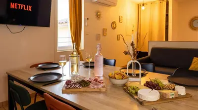 a dining room table with food and wine bottles at Bel Appartement Climatisé avec Terrasse au centre-ville de Narbonne in Narbonne