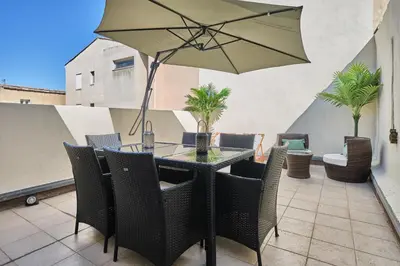 a table with chairs and an umbrella on a patio at Bel Appartement Climatisé avec Terrasse au centre-ville de Narbonne in Narbonne