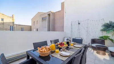 a table with a bowl of fruit on a balcony at Bel Appartement Climatisé avec Terrasse au centre-ville de Narbonne in Narbonne