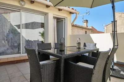 a table with chairs and an umbrella on a patio at Bel Appartement Climatisé avec Terrasse au centre-ville de Narbonne in Narbonne