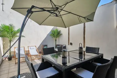a table with chairs and an umbrella on a patio at Bel Appartement Climatisé avec Terrasse au centre-ville de Narbonne in Narbonne