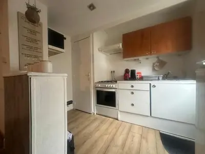 a kitchen with white appliances and a wooden floor at Jolie 2 pièces avec terrasse au centre-ville, proche gare in Narbonne