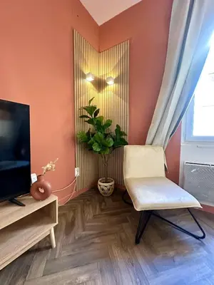 a living room with a chair and a television at Jolie 2 pièces avec terrasse au centre-ville, proche gare in Narbonne