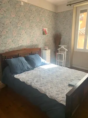 a bedroom with a bed with blue sheets and floral wallpaper at Chambres d hôtes H in Lavelanet