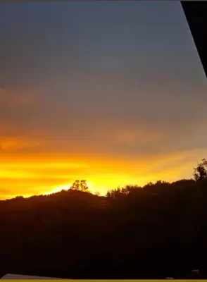 a sunset in the sky with trees in the foreground at maison chalet in Bessède-de-Sault