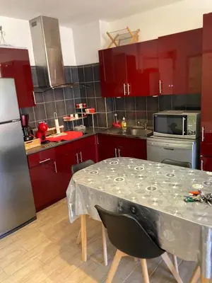 a kitchen with red cabinets and a table with chairs at T2 tout confort - Mer à 200 m in Port-la-Nouvelle