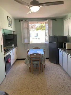 a kitchen with a table and a refrigerator and a window at T1 - Centre ville rez-de-chaussée in Port-la-Nouvelle