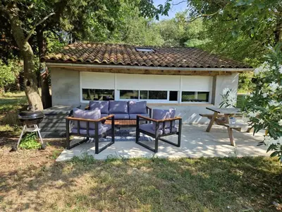 a patio with a table and chairs and a grill at Cottage with large garden in Rieumajou