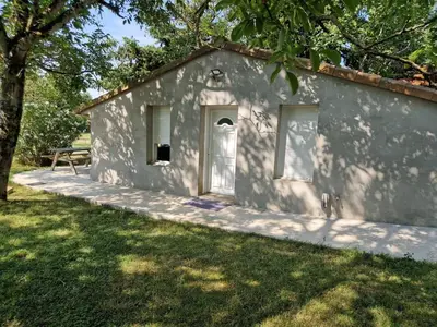a white building with a door and a bench at Cottage with large garden in Rieumajou