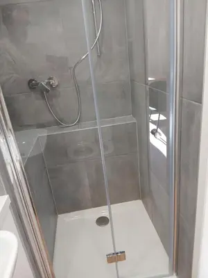 a shower stall with a glass door with a shower at Cottage with large garden in Rieumajou