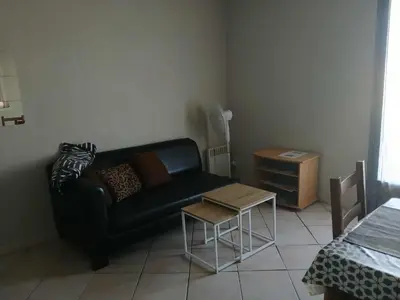 a living room with a black couch and a table at Appartement 2 pièces petit village au calme in Moussoulens