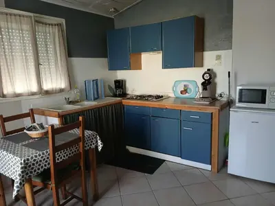 a kitchen with blue cabinets and a table and a microwave at Appartement 2 pièces petit village au calme in Moussoulens
