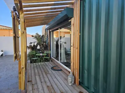 a wooden deck with a glass entrance to a house at Studio Conteneur in Cruscades