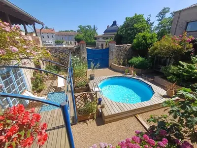 a swimming pool in a garden with a wooden deck at SAINT-JULIA - Studio in Saint-Julia