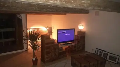 a living room with a television on a stand at La commanderie in Homps