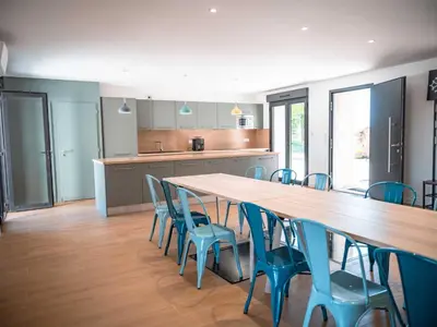 a kitchen with a large wooden table and blue chairs at La Borie Lautrecoise - 26 pers - Piscine chauffée & Clim in Jonquières