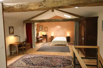 an attic bedroom with a bed and a desk at Le Refuge de Bruno in Saint-Amans-Soult