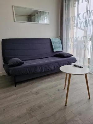a living room with a blue couch and a table at Bord de mer avec piscine intérieure chauffée in Port-la-Nouvelle
