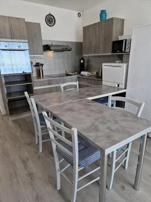 a kitchen with a large wooden table and chairs at Bord de mer avec piscine intérieure chauffée in Port-la-Nouvelle