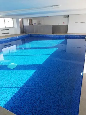 a large swimming pool with blue tiles on the floor at Bord de mer avec piscine intérieure chauffée in Port-la-Nouvelle