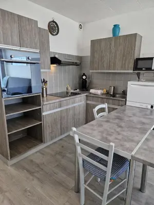 a kitchen with wooden cabinets and a table and chairs at Bord de mer avec piscine intérieure chauffée in Port-la-Nouvelle