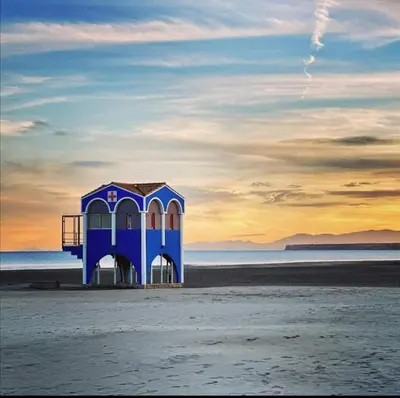 a blue lifeguard shack on the beach at sunset at Bord de mer avec piscine intérieure chauffée in Port-la-Nouvelle