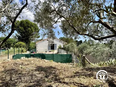 a small white house with a green fence at Le gite aux oliviers in La Redorte