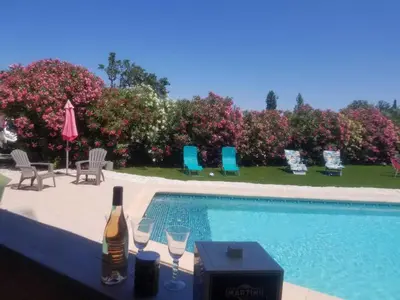 a bottle of wine sitting on a table next to a swimming pool at Le gite aux oliviers in La Redorte