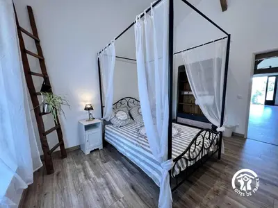 a bedroom with a bed with a canopy at Le gite aux oliviers in La Redorte