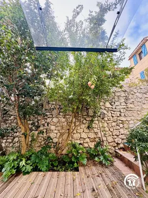 a stone wall with trees on a wooden deck at La maisonnette in Bages