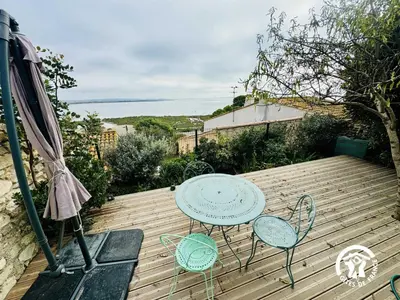 a wooden deck with a table and chairs and an umbrella at La maisonnette in Bages