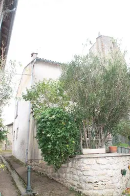 a stone wall with trees in front of a building at Chambre 2 in Saint-Michel-de-Lanès